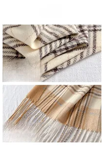 Detailansicht der weichen beige-karierten Schal-Textur und der feinen Fransenkanten am Saum