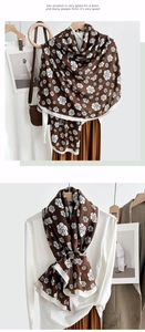 Detailed view of dark brown scarf with white camellia floral pattern as a stylish shawl