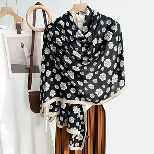 Elegant black camellia flower scarf draped over wooden hanger in a lifestyle setting