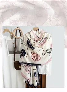 Detail of elegant linen scarf with pink roses and modern lettering on a wooden hanger
