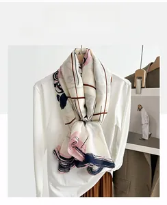 Detailed view of beige scarf with camellia rose patterns styled over a white blouse