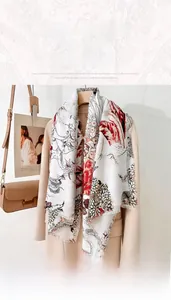 Détail de l'élégante écharpe crème à feuilles d'érable et franges sur manteau