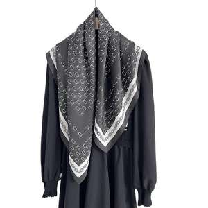 Elegant black and white chain pattern silk scarf styled on a black long-sleeved dress