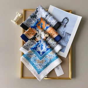 Detail of three printed silk scarves in a gold frame with floral and geometric patterns