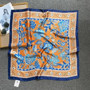 Flat lay detail of floral satin square scarf in orange and blue with chic fashion props