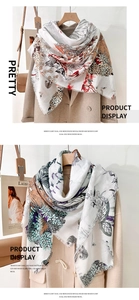 Détail d'une écharpe en laine mercerisée à imprimé floral, motifs papillons et doux pompons