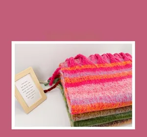 Gros plan sur la texture de l'écharpe en tricot à rayures avec des glands épais et colorés