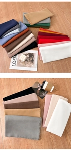 Flat lay of multiple solid color scarves with fringes on a wood background