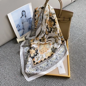 Detailed close-up of a vintage square silk scarf with floral paisley patterns on a satin texture