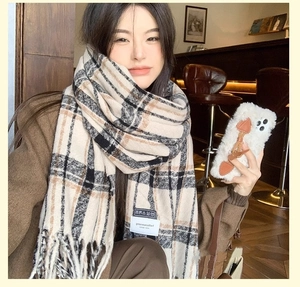 Detailed view of beige and brown plaid cashmere scarf with long fringe on model