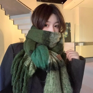 Close-up of thick dark green plaid scarf with long tassels and premium leather label