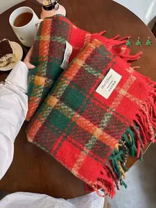 Nahaufnahme von rot-grünem Karo-Schal mit Quasten und weißem Markenetikett für Winter