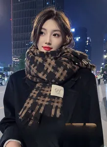 Detail of winter checkered scarf in dark brown and black featuring a branded logo tag