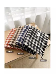 Close-up of houndstooth scarves in red, khaki, blue, and black with fringe details
