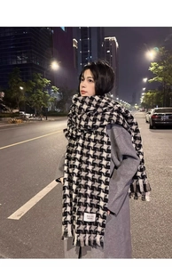 Detailed shot of black and white houndstooth scarf with tassels on a wool coat