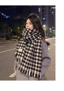 Detail of black and white checkered scarf with fringe and fabric care label tag