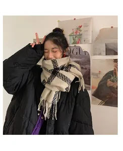 Détail d'une écharpe à carreaux beige et noir avec franges et veste matelassée