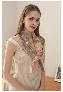 Elegant paisley and floral silk-like scarf in earth tones worn over a beige knit dress