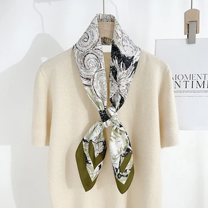 Elegant silk scarf with green artistic swirl patterns on a knitted top display