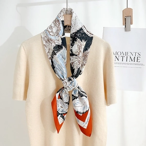 Elegant white silk square scarf with blue floral prints and orange borders on beige knitwear