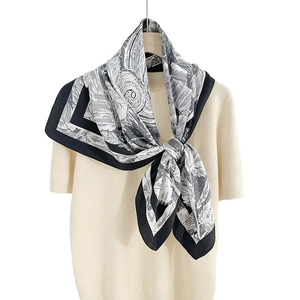 Elegant black and white abstract print silk square scarf styled on a beige knit sweater