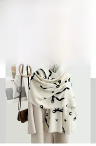 Detail eines weichen cremefarbenen Pashmina-Schals mit Schleifendruck und Fransen am Bügel