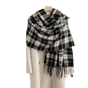 Classic black and white checkered scarf with tassel trim on a beige winter coat
