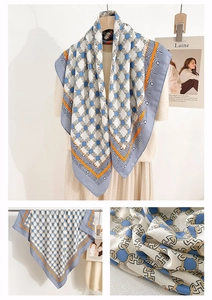 Detail of elegant square silk scarf featuring H-chain link pattern and vibrant blue hues