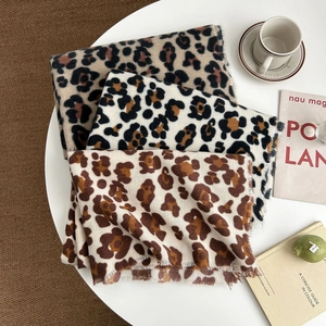 Trois écharpes en cachemire à imprimé léopard avec franges sur une table moderne