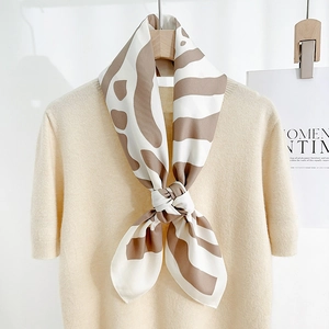 Élégant foulard en soie rayé pour femme porté sur un haut en maille beige style bureau
