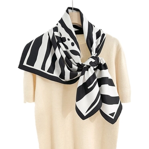 Carré de soie élégant à motif zébré noir et blanc noué sur un haut en maille chic