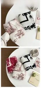 Détail de l'écharpe en maille à imprimé abstrait rouge et marron avec des franges