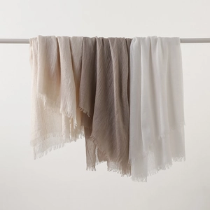 Lightweight cotton linen scarves with fringe edges in neutral earth tones hanging on a rod