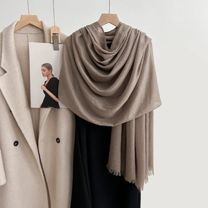 Elegant warm brown linen scarf with fringe edges paired with a beige coat and black dress
