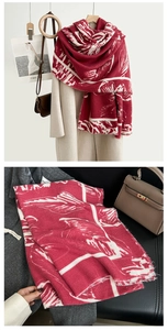 Détail d'une écharpe bordeaux aspect cachemire avec motif plumes et franges sur manteau beige