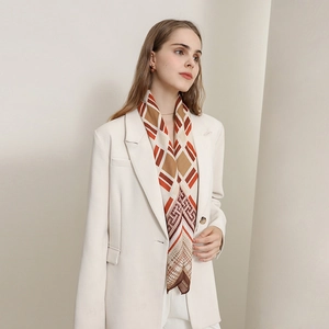 Elegant geometric print silk scarf in orange and brown paired with a white blazer