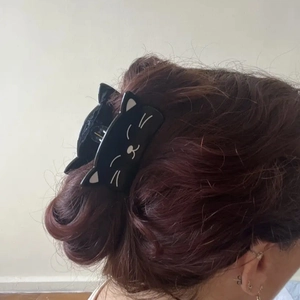 Vista detallada de una pinza para el pelo de gato negro usada en un peinado semirecogido