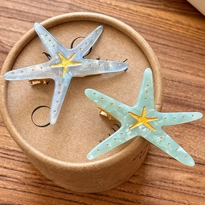 Detailed view of two marble textured starfish hair clips in blue and mint green colors