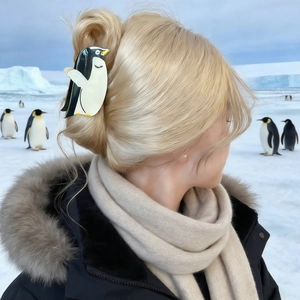 Détail d'une pince à cheveux pingouin sur cheveux blonds avec fond de glacier arctique