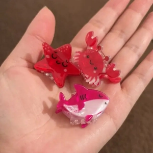 Detailed view of small acrylic sea animal hair clips in crab starfish and shark shapes
