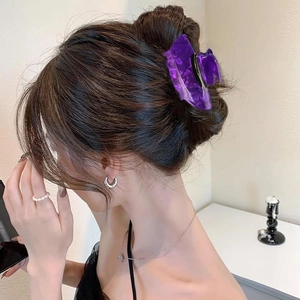 Detail of a deep purple translucent hair claw clip securing a thick ponytail in a stylish bun