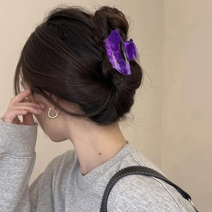Close-up of a purple translucent witch hat hair claw clip worn on a woman's ponytail