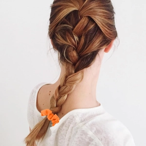 Detail of vibrant orange chiffon scrunchie worn on a ponytail for daily hairstyling