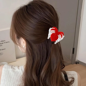 Dettaglio della molletta per capelli con mani di scheletro e cuore di paillettes rosse