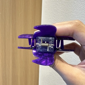 Handheld view of a transparent purple witch hat hair claw clip for a creative ponytail look