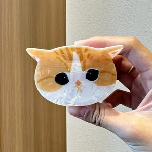 Vue détaillée d'une pince à cheveux chat orange en acétate avec une texture nacrée fine