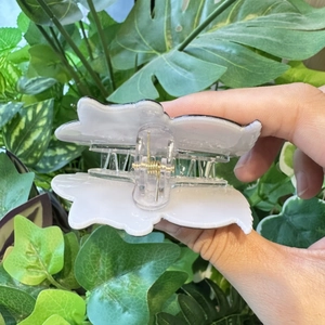 Handheld Halloween devil pumpkin hair claw clip in translucent cream on green leaves