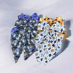 Macro detail of large Halloween bows with pumpkin, ghost, and bat patterns on marble
