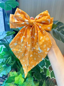 Détail d'un nœud papillon de Noël orange avec motifs de rennes et flocons de neige