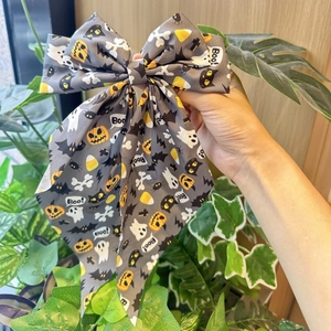 Close-up of Halloween bow hair clip featuring pumpkin, ghost, and cat prints on dark fabric